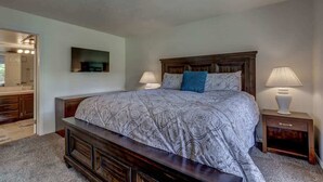A bedroom with a large bed, two bedside tables, a nightstand, and a mirror. - Las Palmas Resort #1406 | All-Inclusive Amenities (Saint George)
