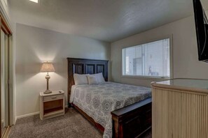 A bedroom with a bed, bedside table, lamp, and window.