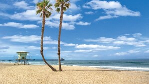 A beach with two palm trees, a lifeguard tower, and a pier in the background. - Premium Beachfront Stay Ground Floor, 2 Parking Spots,  Community Jacuzzi EV Charging (Oceanside)