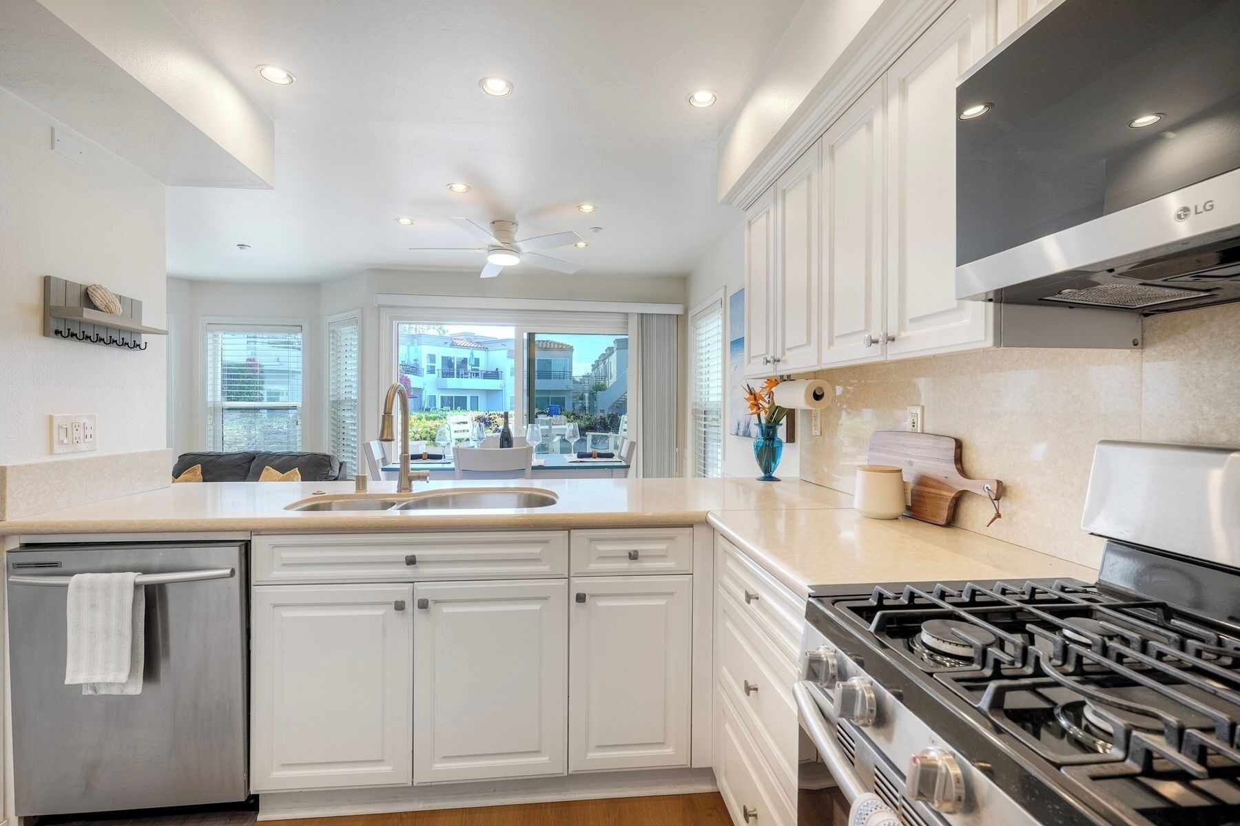 A modern kitchen with white cabinetry, a stainless steel refrigerator, a gas stove, and a ceiling fan.