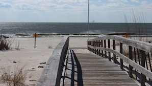A wooden boardwalk leading to the beach with a clear view of the ocean.