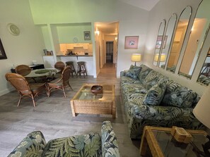 Un salon comprenant un canapé, des fauteuils, une table basse et un coin repas avec une table et des chaises.