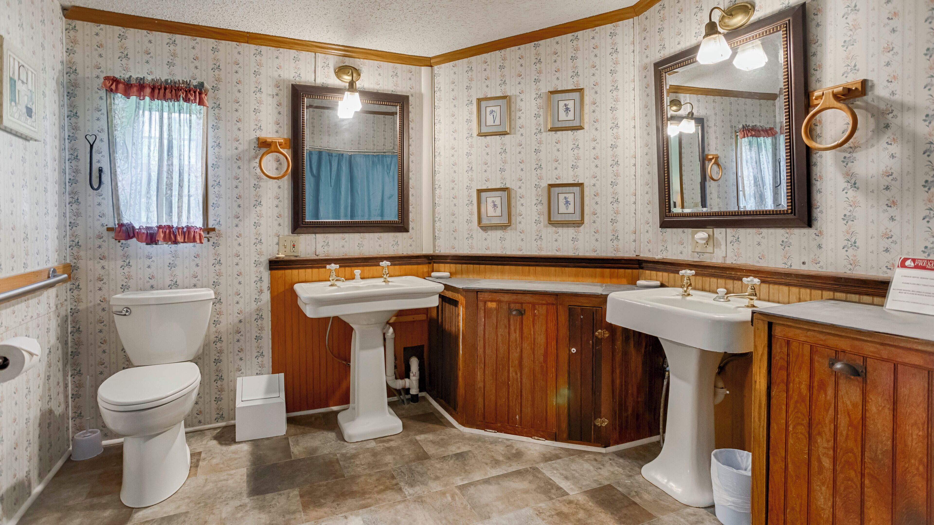 Un baño con dos lavamanos, un inodoro y un espejo.