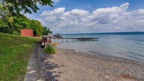A lakeside dock with boats, a red building, and a gravel path.