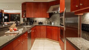 Een moderne keuken met houten kastjes, granieten aanrecht en roestvrijstalen apparatuur, verlicht met inbouwspots.