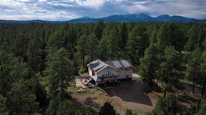 Une maison entourée d’une forêt dense, offrant une vue dégagée sur les montagnes lointaines.