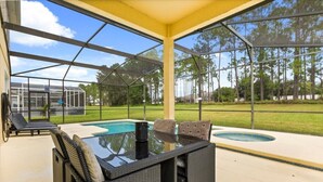 A covered outdoor area with a pool, lounge chairs, and a glass table. - EV_116 - 6BR / 4.5BA Highlands Reserve Villa near Disney, Private Pool & Spa (Davenport)