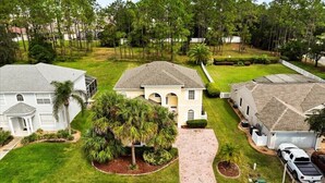 A residential area with two houses, one with a large driveway and a garage, and the other with a smaller driveway and a garage. - EV_116 - 6BR / 4.5BA Highlands Reserve Villa near Disney, Private Pool & Spa (Davenport)