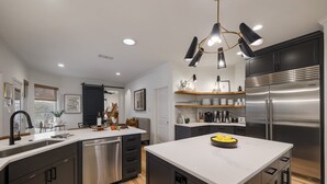 Una cocina moderna con una isla central, electrodomésticos de acero inoxidable y una decoración en blanco y negro.