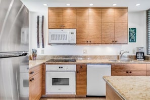Une cuisine moderne avec des meubles en bois, des appareils en acier inoxydable et des plans de travail en granit.