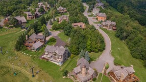 Vue aérienne d’un quartier résidentiel avec de nombreuses maisons, une route sinueuse et un télésiège.