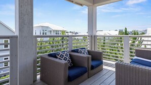 Ein überdachter Balkon mit Korbmöbeln und Blick auf umliegende Häuser.