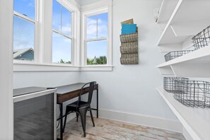 A compact room with a desk, chair, and shelving unit.