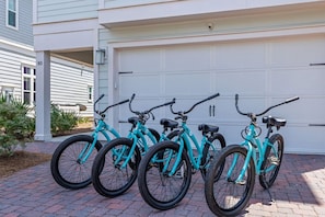 Une rangée de vélos turquoise est garée devant une porte de garage blanche.