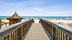 A wooden boardwalk leading to a beach with a thatched-roof hut. - WELL APPOINTED & ELEGANT CONDO! GULF FRONT WITH SWEEPING VIEW (Destin)