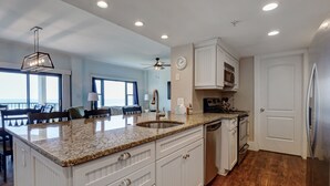 A modern kitchen with granite countertops, white cabinetry, and a built-in dishwasher. - DR 2211–Simply elegant oceanfront condo with expansive views, pool and tennis (Wrightsville Beach)