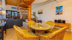 Amplia sala de estar con una escalera espiral de madera, muebles de mimbre y vistas al exterior.