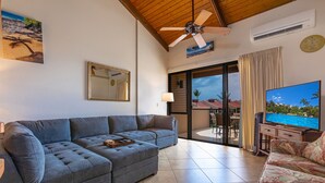 Una sala de estar con un sofá modular, un televisor y un ventilador de techo.