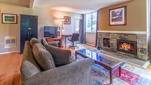 A living room with a fireplace, a sofa, a TV, and a desk. - Mountain Condo Near Gondola & Village 249 (Mammoth Lakes)