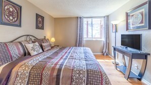 A bedroom with a bed, a TV, a desk, and a window with curtains. - Mountain Condo Near Gondola & Village 249 (Mammoth Lakes)