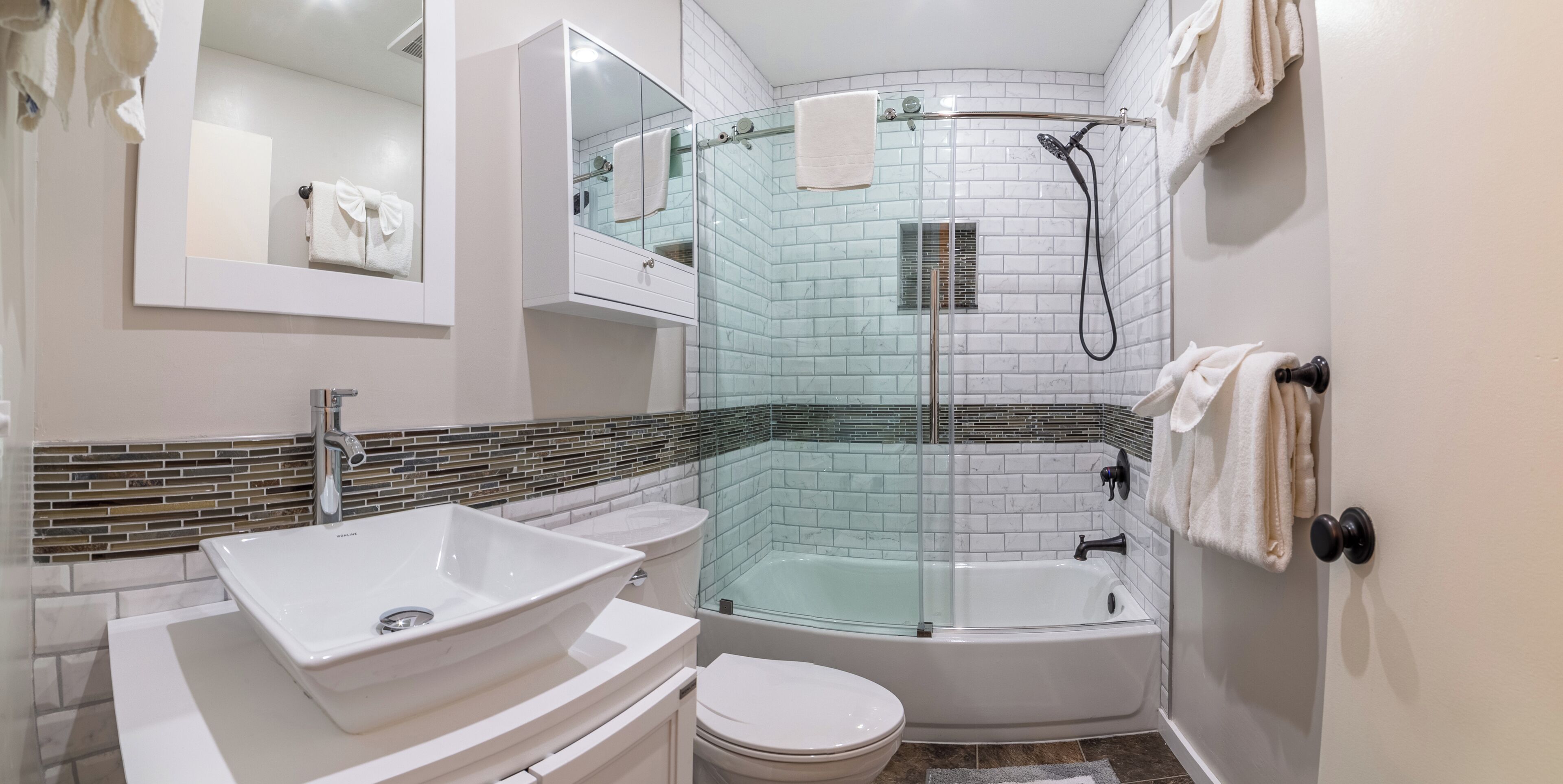 A modern bathroom with a glass-enclosed shower, a white sink, and a toilet.
