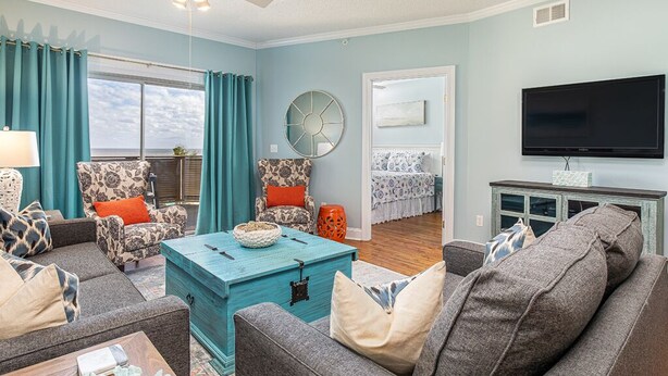 A living room with a sofa, armchairs, a coffee table, and a television. - Sandpiper 203 | Oceanfront with Great Views! (Tybee Island)