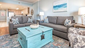 A living room with two gray sofas, a turquoise coffee table, and a patterned rug. - Sandpiper 203 | Oceanfront with Great Views! (Tybee Island)