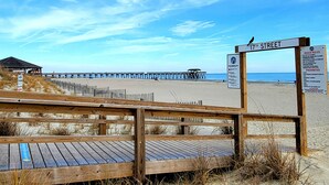 A wooden boardwalk leading to a beach with a pier in the background. - Sandpiper 203 | Oceanfront with Great Views! (Tybee Island)