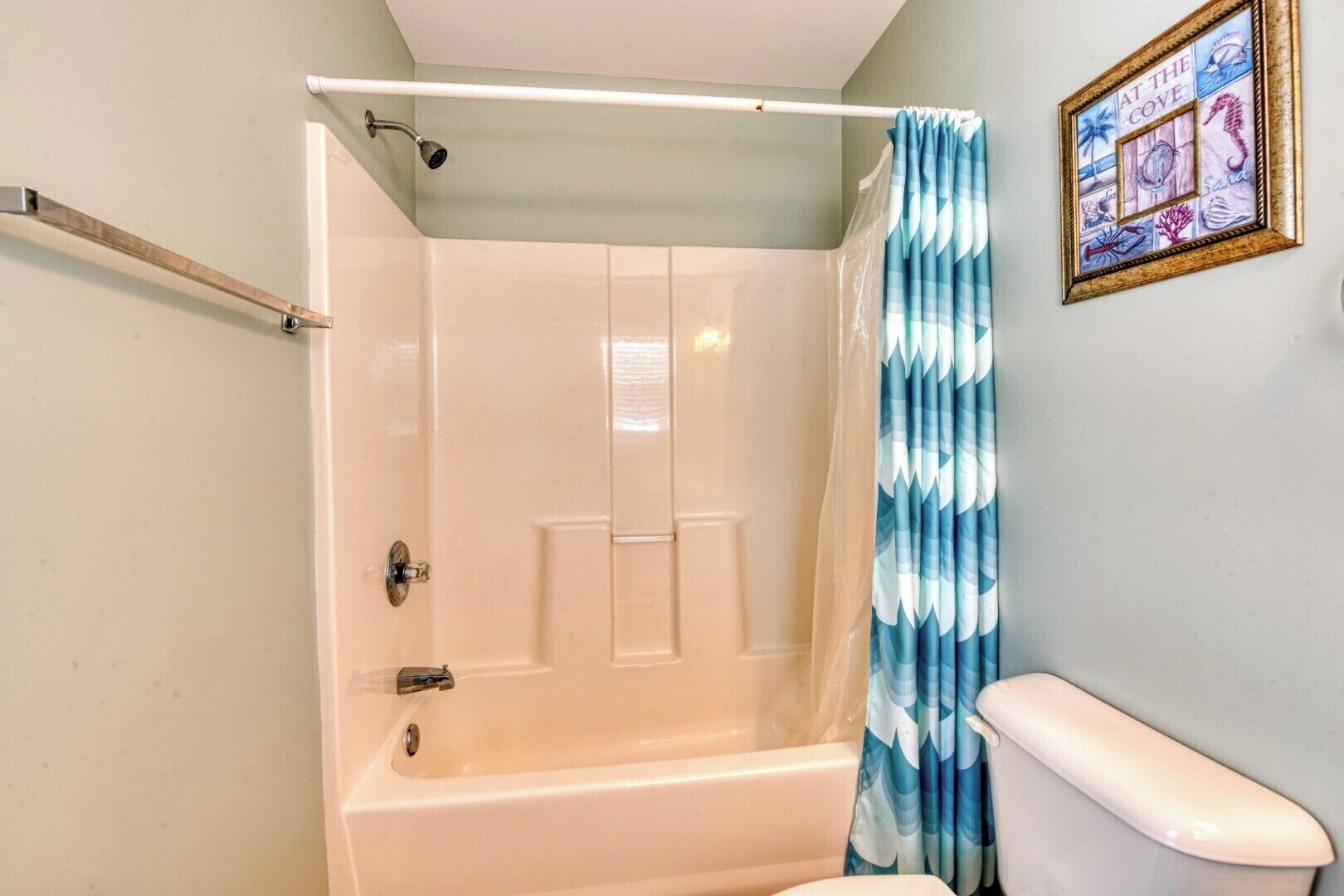 A bathroom with a bathtub, a shower curtain, and a toilet.
