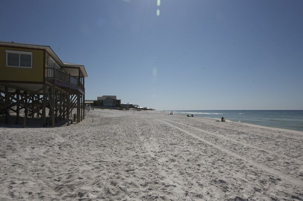 A beach with a wooden pier structure and a building on stilts.