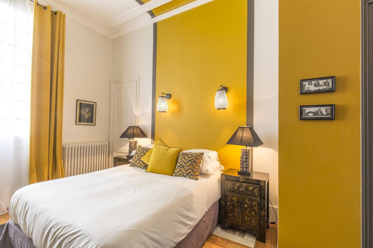 Ein Schlafzimmer mit einem großen Bett, zwei Nachttischen mit Lampen, einem Heizkörper und zwei Wandleuchten.