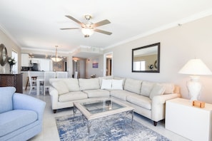 A living room with a sectional sofa, a coffee table, and a blue rug.