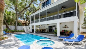 Une maison à deux étages avec une piscine, un espace salon extérieur et une terrasse couverte.