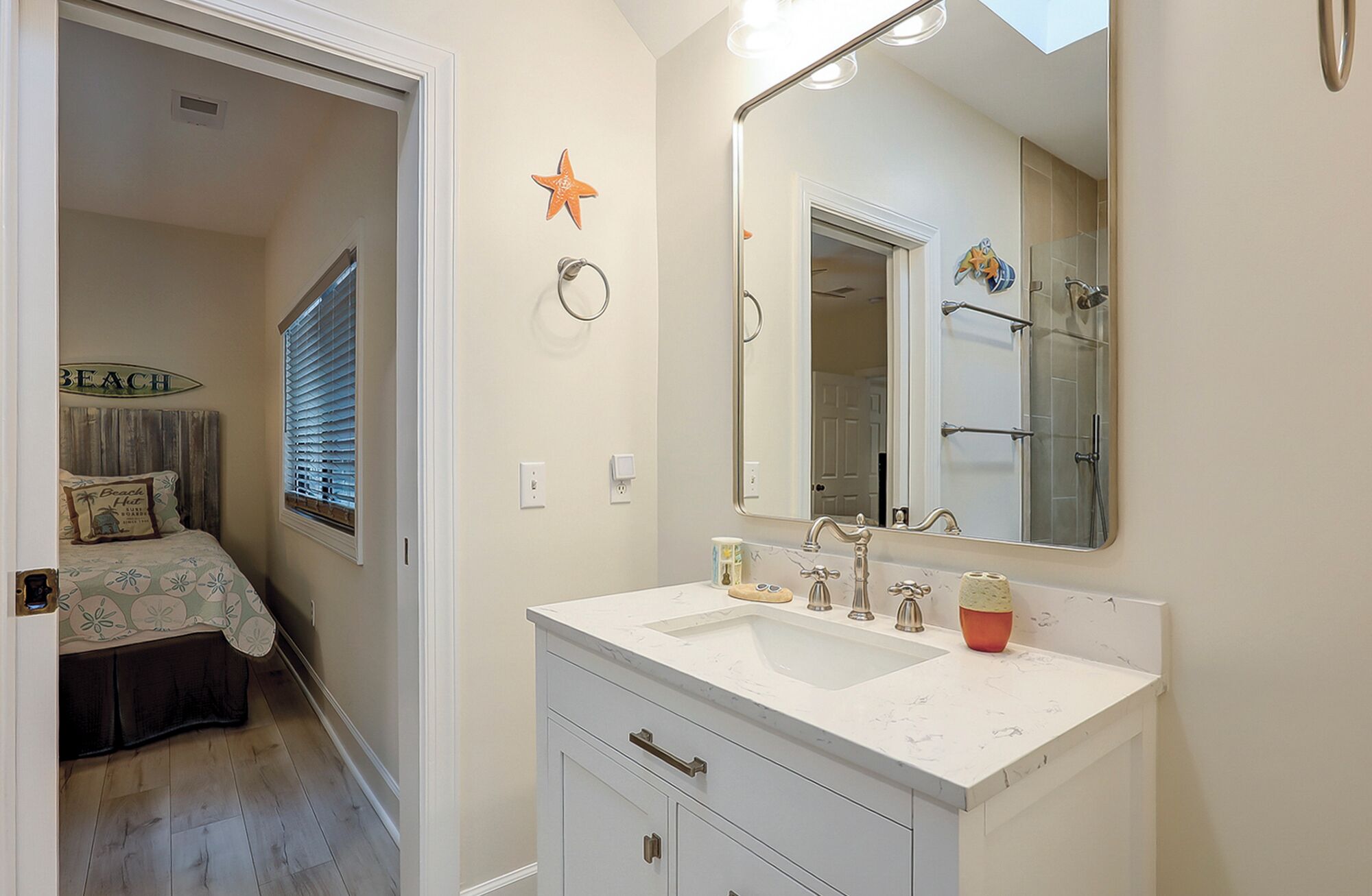 A bathroom with a white vanity, a large mirror, and a shower area.