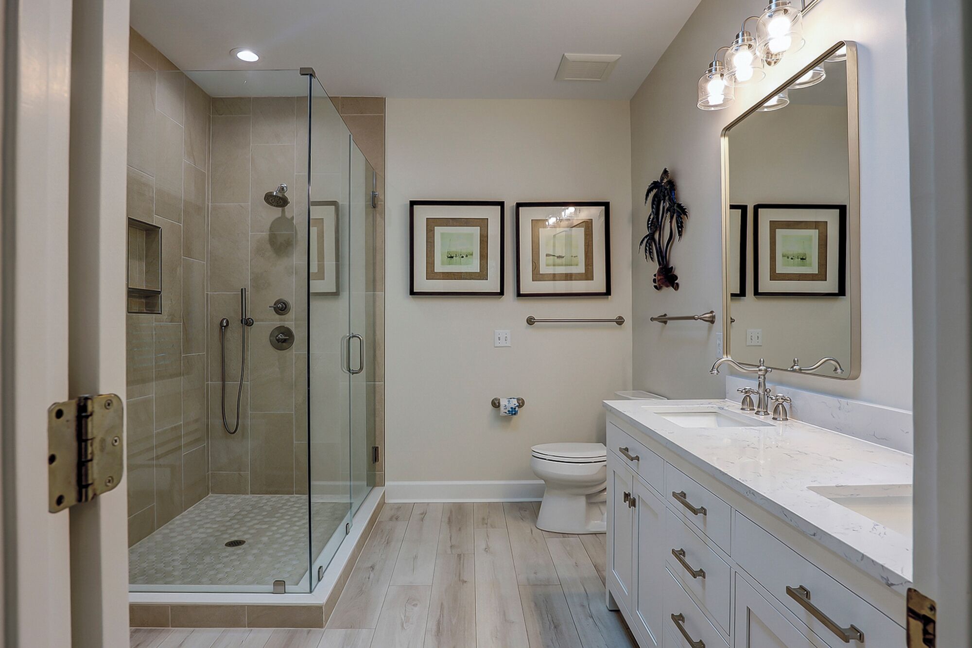 A modern bathroom with a glass-enclosed shower, a toilet, and a vanity with a large mirror.
