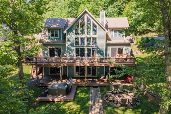 A two-story house with a deck, a fire pit, and a covered outdoor seating area.