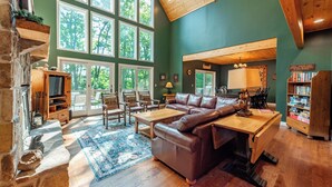 Un salon spacieux doté d’une grande fenêtre, d’une cheminée, d’un canapé en cuir et d’une table basse en bois.