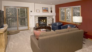 A living room with a fireplace, a sofa, a television, and a large window.