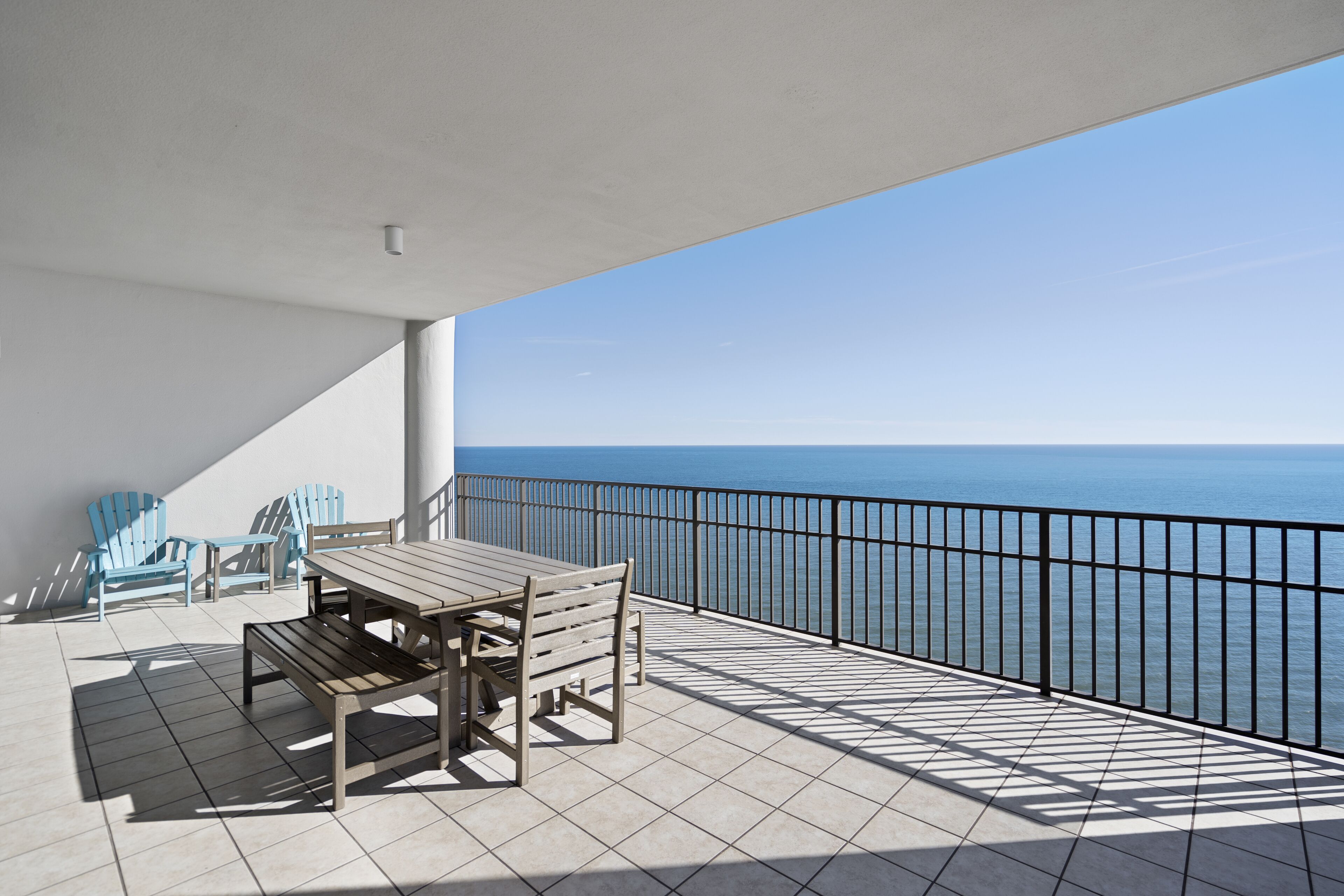 A balcony with a table and chairs, a view of the sea, and a tiled floor.