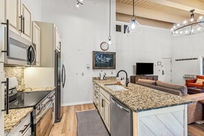 Eine moderne Küche mit Granit Arbeitsplatten, Edelstahlgeräten und einer integrierten Kochinsel.