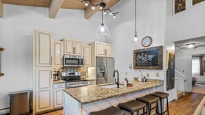 A kitchen with granite countertops, stainless steel appliances, and a bar area with stools.