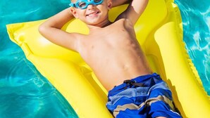 A child lying on a yellow inflatable float in a swimming pool.