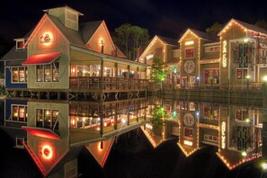A waterfront building with multiple levels, including a docked boat, and a reflection in the water.