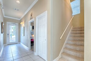 A hallway with a carpeted staircase, a white door, and a light fixture on the wall. - Vacation Starts Poolside–Heated Private Pool & Golf Cart Available (Santa Rosa Beach)