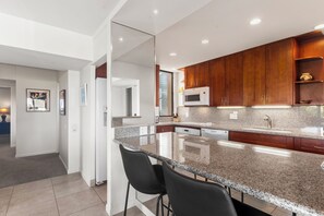 Una cocina moderna con encimeras de granito, armarios de madera y un lavamanos de acero inoxidable.