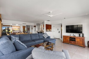 A modern living room with a large sofa, a coffee table, and a TV on a wooden cabinet.