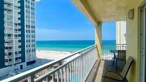 Un balcon donnant sur une plage et un immeuble de grande hauteur.
