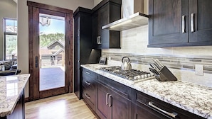Una cocina moderna con gabinetes de madera oscura, encimera de granito y estufa a gas.