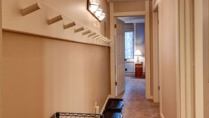 A hallway with a staircase, a wall-mounted light fixture, and a door leading to another room. - Peak 8 Village Hideaway Condo: On Shuttle Route (Breckenridge)