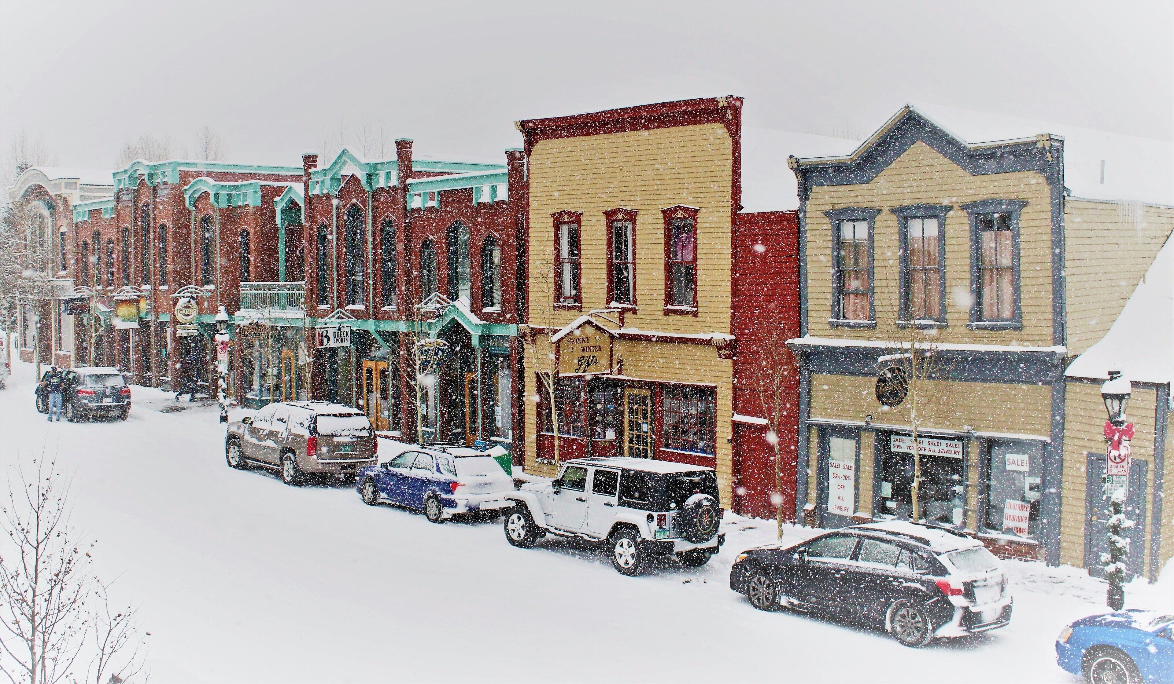 A row of multi-story buildings with storefronts on a snowy street.